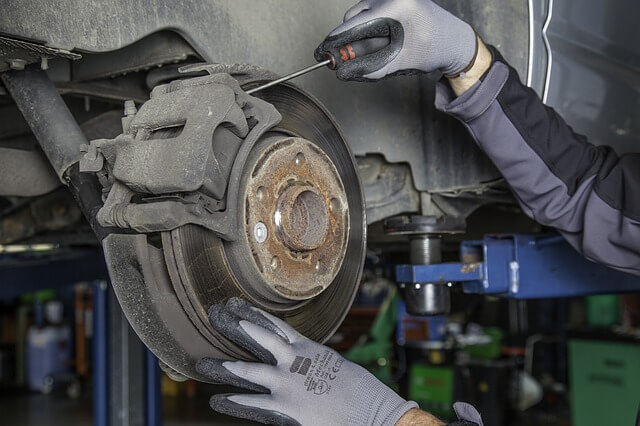 Mann wechselt Bremsscheibe am Auto.